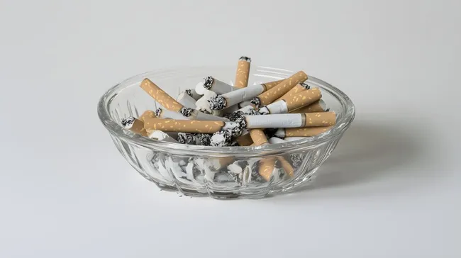 Zigarettenstummel in zerknittertem Glas