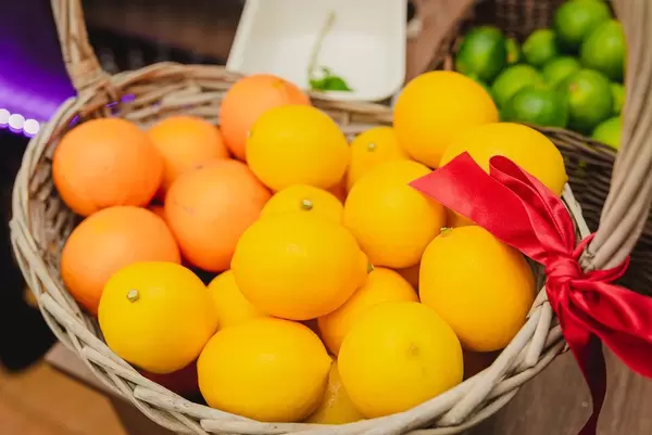 Zitronen und Orangen in einem Holzkorb - im Hintergrund Limetten