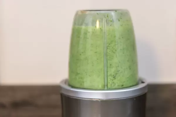 Zubereitung eines grünen Proteindrinks im Mixer, für eine sportliche, gesunde Ernährung