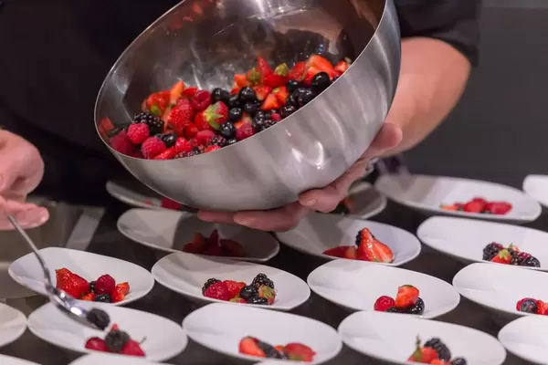 Zubereitung vieler Portionen eines Obstsalates mit unterschiedlichen Beeren