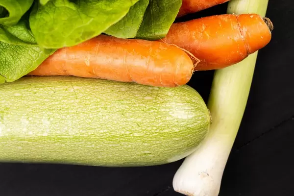 Zucchini-Karotten und Lauch auf der schwarzen Tischplatte