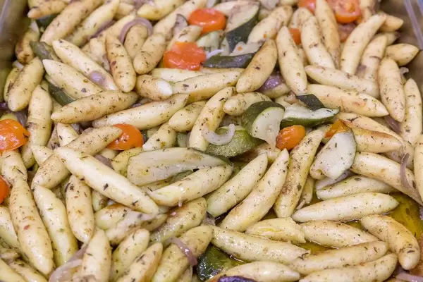 Zucchini potato dumplings pan with tomatoes and onions at the buffet in close-up