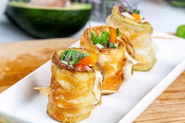 Zucchini rolls with vegetables and cheese sauce