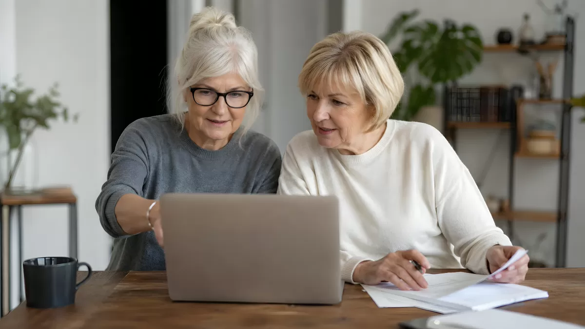 Zwei ältere Frauen arbeiten gemeinsam am Laptop