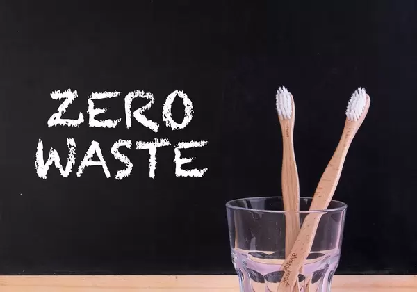 Zwei Bambuszahnbürsten im Zahnputzbecher, neben dem Text "Zero Waste"