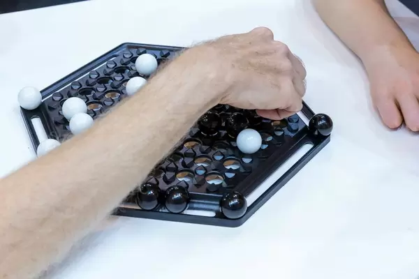 Zwei Besucher der SPIEL 19 Messe in Essen spielen Brettspiel Abalone mit sechseckigen Spielfeld und schwarzen und weißen Kugeln