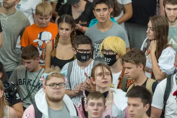 Zwei Besucher mit schwarzem Mundschurz in der Masse