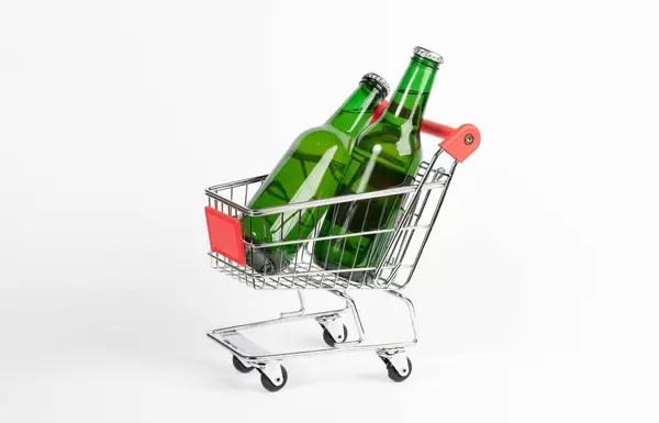 Zwei Bierflaschen stehen in Einkaufswagen vor weißem Hintergrund