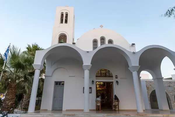 Zwei Damen sitzen auf Stühlen vor dem Eingang der heiligen Pfarrkirche Pantanassis in Naoussa auf Paros