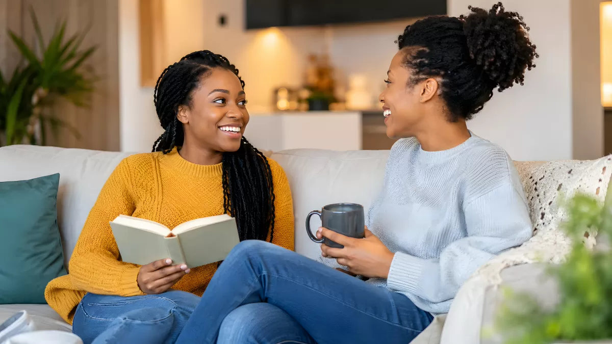 Zwei Freundinnen auf dem Sofa beim Lesen und Plaudern