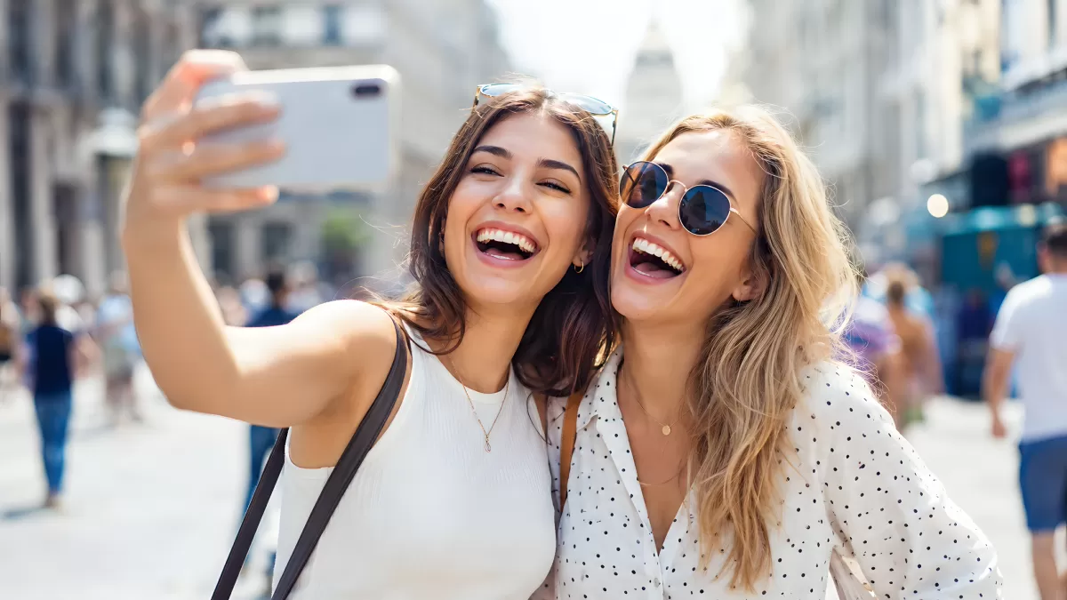 Zwei Freundinnen machen lachend ein Selfie in der Stadt