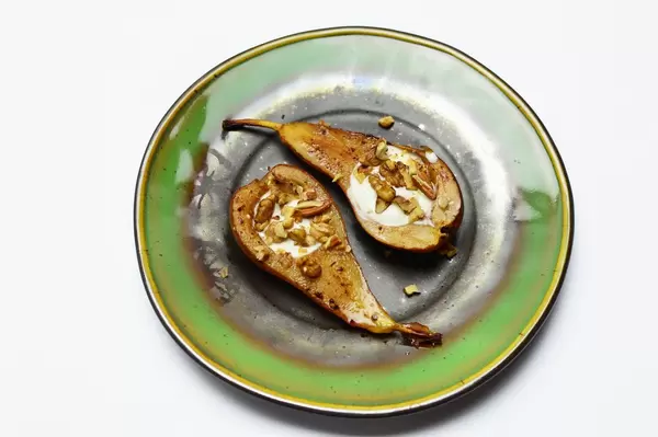 Zwei gebackene halbe Birnen mit gehackten Nüssen auf grünem Teller