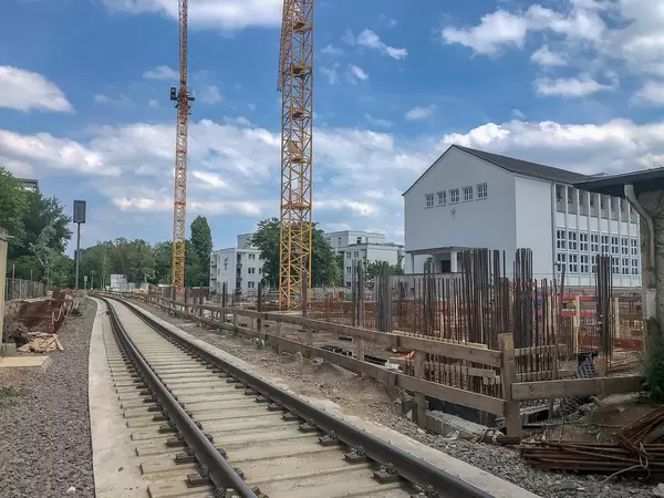 Zwei gelbe Kräne auf der Baustelle Clarenbachstift, neben der Gleisstrecke in Köln