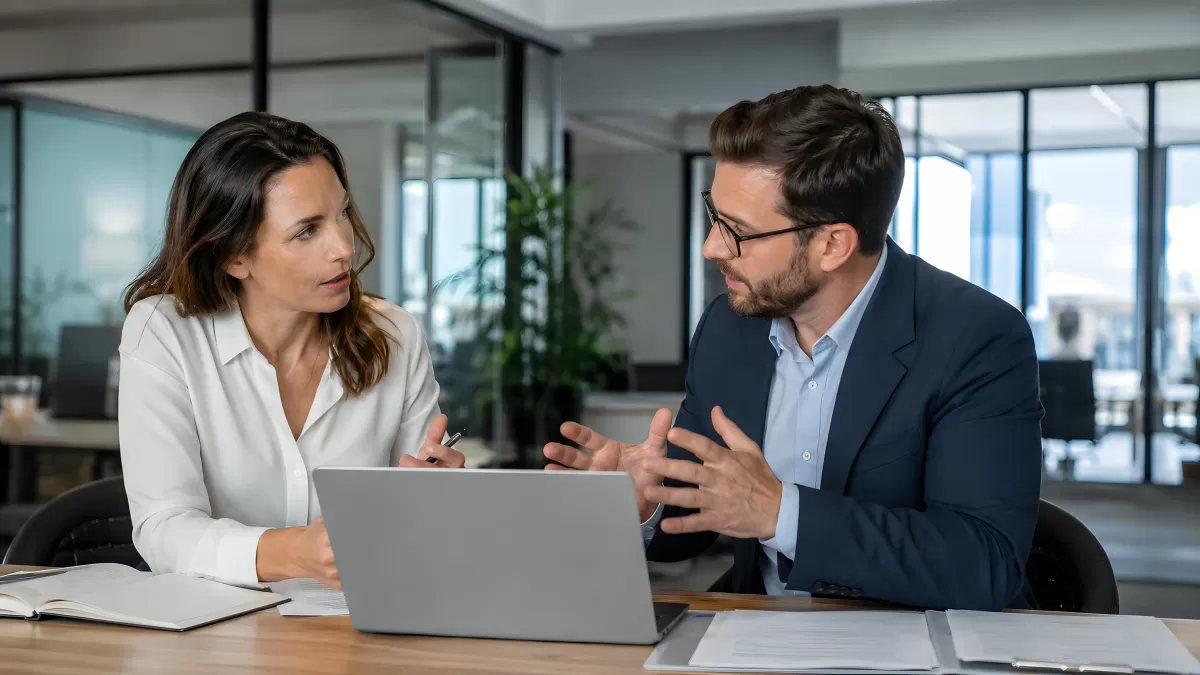 Zwei Geschäftsleute im Gespräch am Laptop im Büro