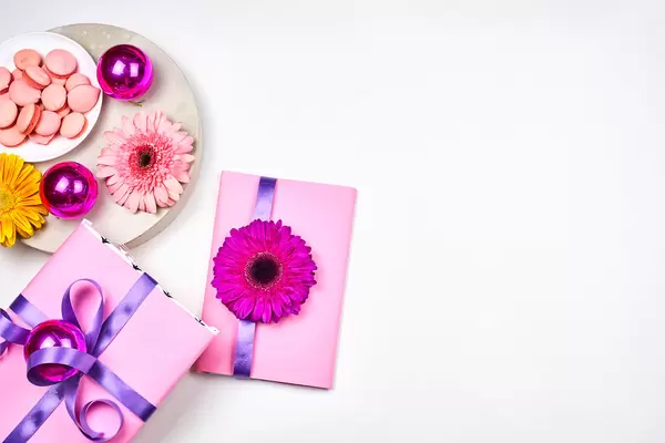 Zwei Geschenke in Rosa gepackt und Party-Deko. Weißer Hintergrund mit Platz für Text rechts