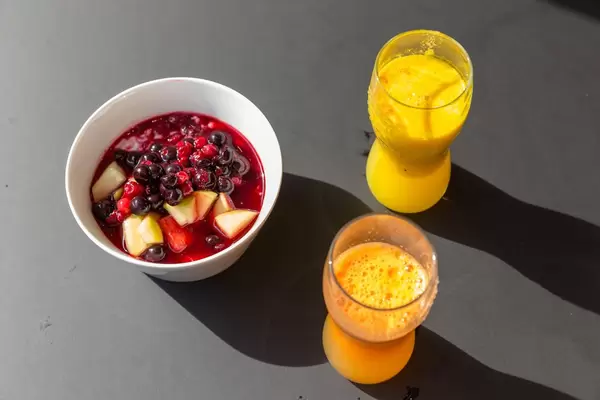 Zwei Gläser Orangensaft und ein Fruchtsalat mit Kirsche, Sauerkirsche, Apfel und Wassermelone