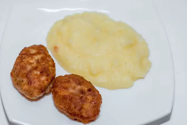 Zwei goldbraune Schnitzel mit Portion Kartoffelpüree auf weißem Teller