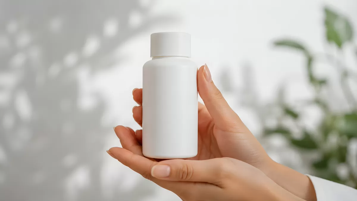 Zwei Hände halten eine weiße Pillendose vor hellem Hintergrund