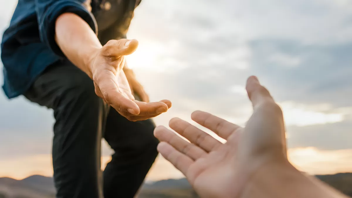 Zwei Hände reichen sich gegenseitig Hilfe beim Wandern