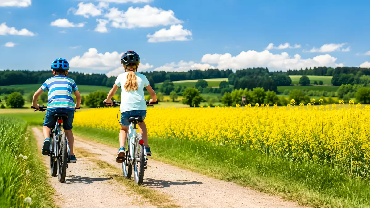 Zwei Kinder fahren Fahrrad auf Feldweg im Sommer