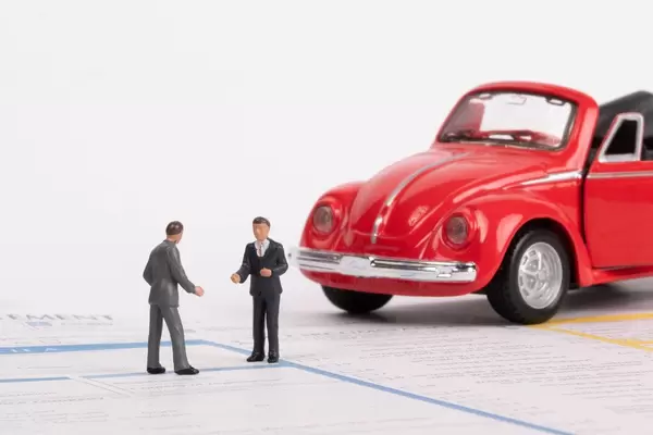 Zwei Männer und ein Oldtimer-Spielzeugauto auf einem Verkehrsunfallbericht