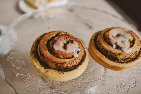 Zwei Mohnblumen-Teilchen mit Zuckerguss, auf einem Glasteller