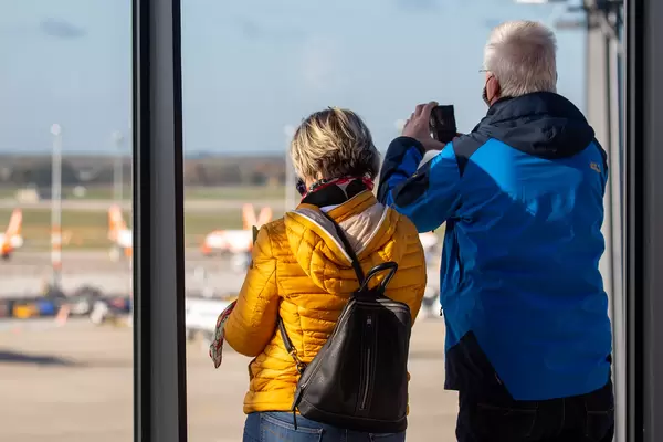 Zwei Passagiere mit Mundschutz fotografieren die Flieger aus der Flughafen BER Besucherterrasse