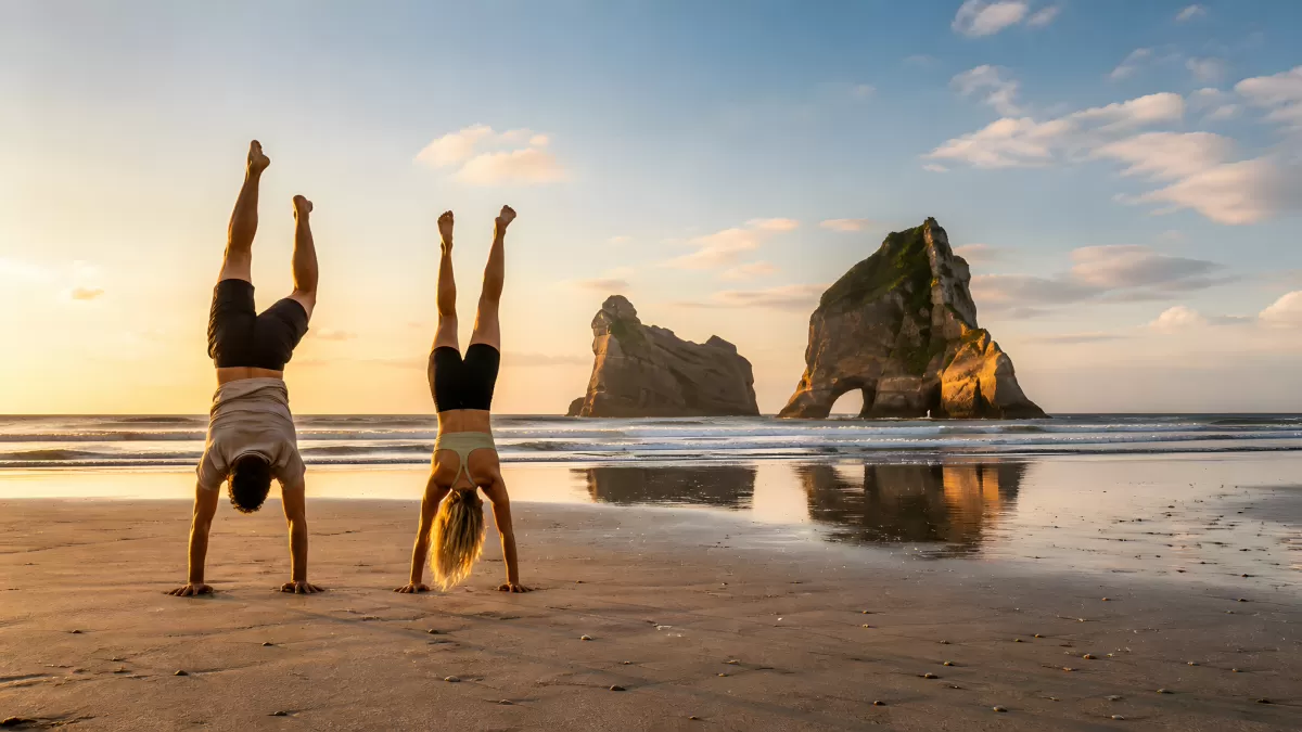 Zwei Personen machen Handstand am Strand bei Sonnenuntergang