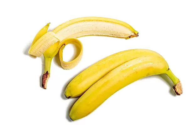 Zwei reife ganze Bananen und eine geschälte auf weißem Hintergrund