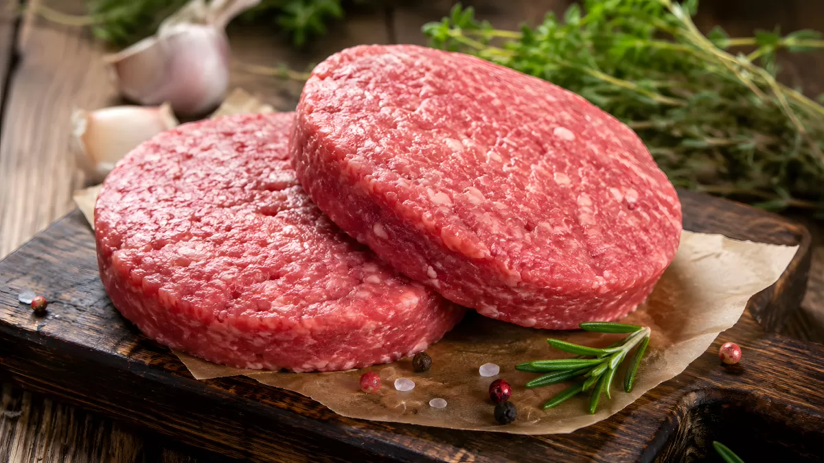 Zwei rohe Rindfleisch-Burger-Patties auf Holzbrett