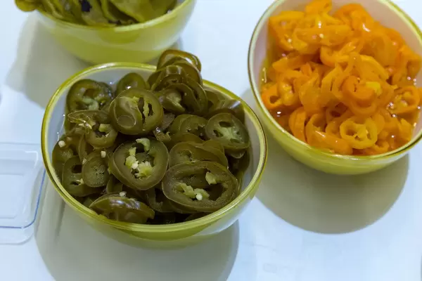 Zwei Schüsseln mit Jalapeños und gelben Chilis in Scheiben geschnitten
