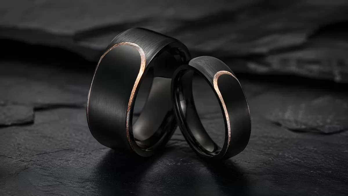 Zwei schwarze Partnerringe mit Roségold-Inlay auf Schiefer
