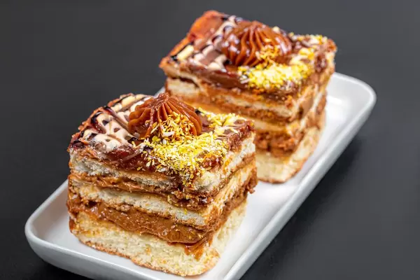 Zwei Stückchen Kuchen mit gekochter Kondensmilch und Kokosraspeln auf weißem Teller