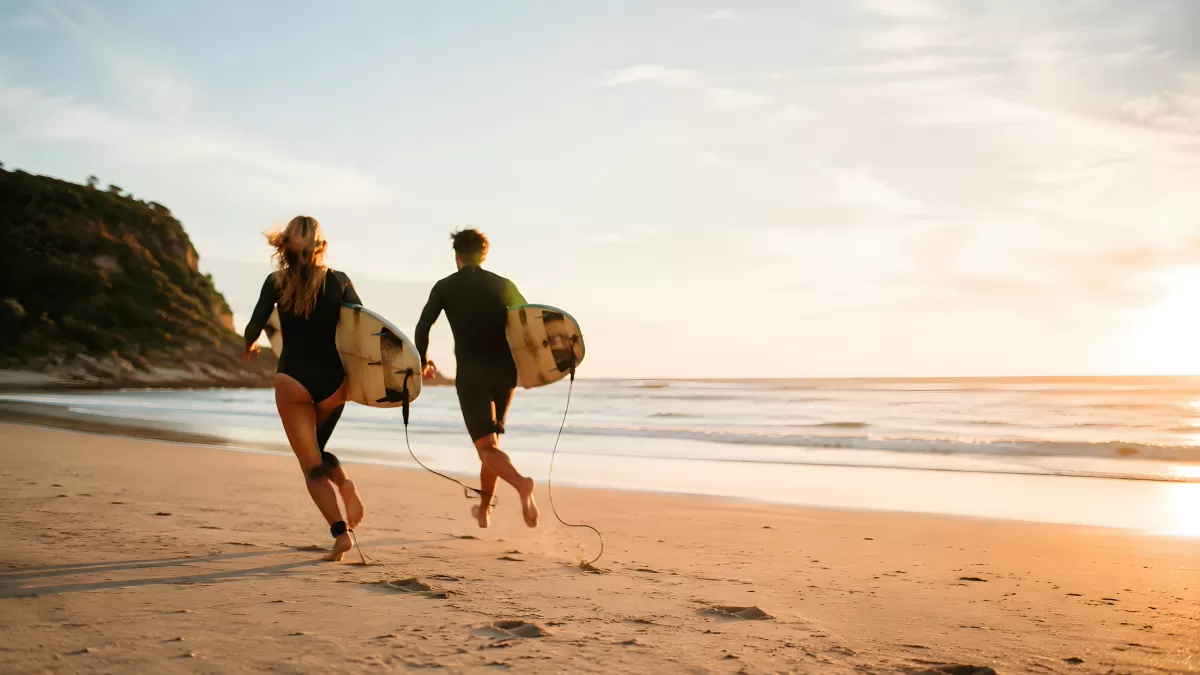 Zwei Surfer laufen bei Sonnenuntergang ans Meer