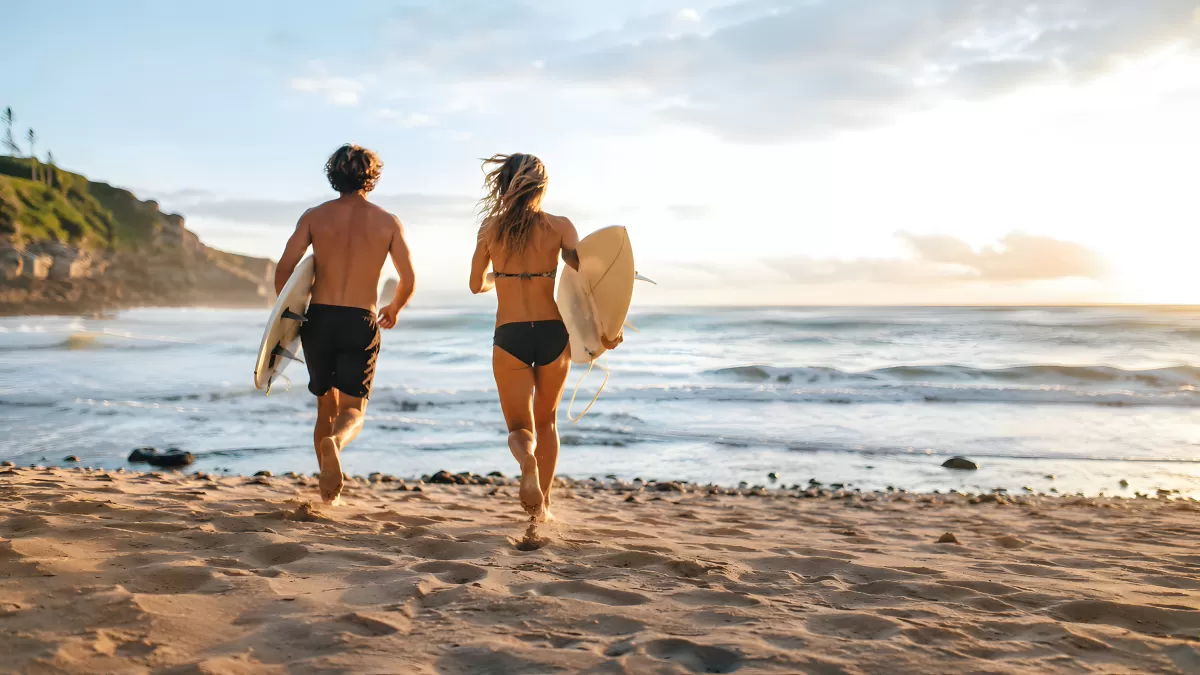 Zwei Surfer schreiten bei Sonnenuntergang ans Meer