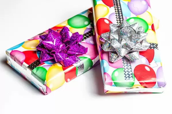 Zwei verpackte Geburtstagsgeschenke auf einem weißem Tisch