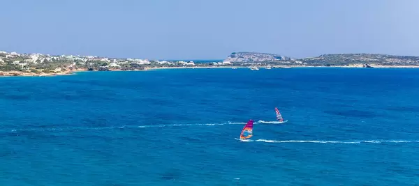 Zwei Windsurfer surfen in entgegengesetzte Richtungen, vor der Santa Maria Strandküste von Paros, Griechenland