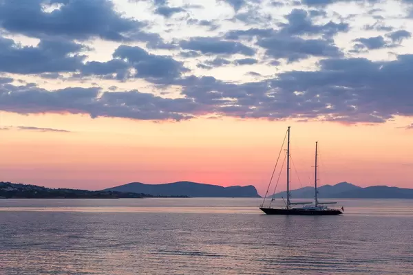 Zweimaster-Segelboot auf dem Meer, mit Sonnenuntergang und rötlichem Himmel im Hintergrund
