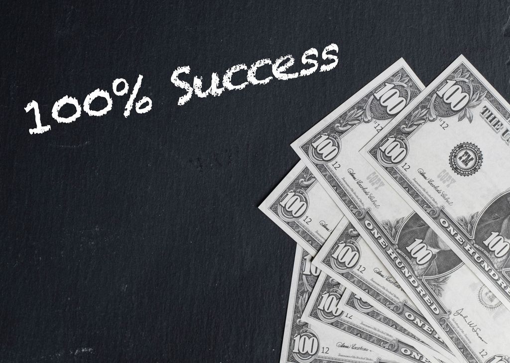 100% Success text with US dollar banknotes