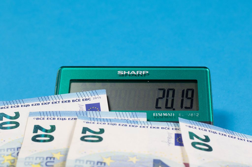 2019 steht auf dem Display eines Sharp Taschenrechners mit Geldscheinen auf blauem Hintergrund