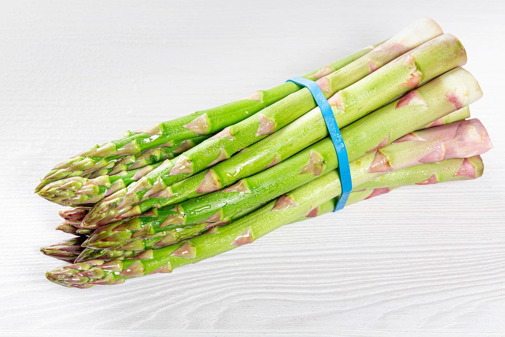 A bunch of fresh asparagus on a white wooden table