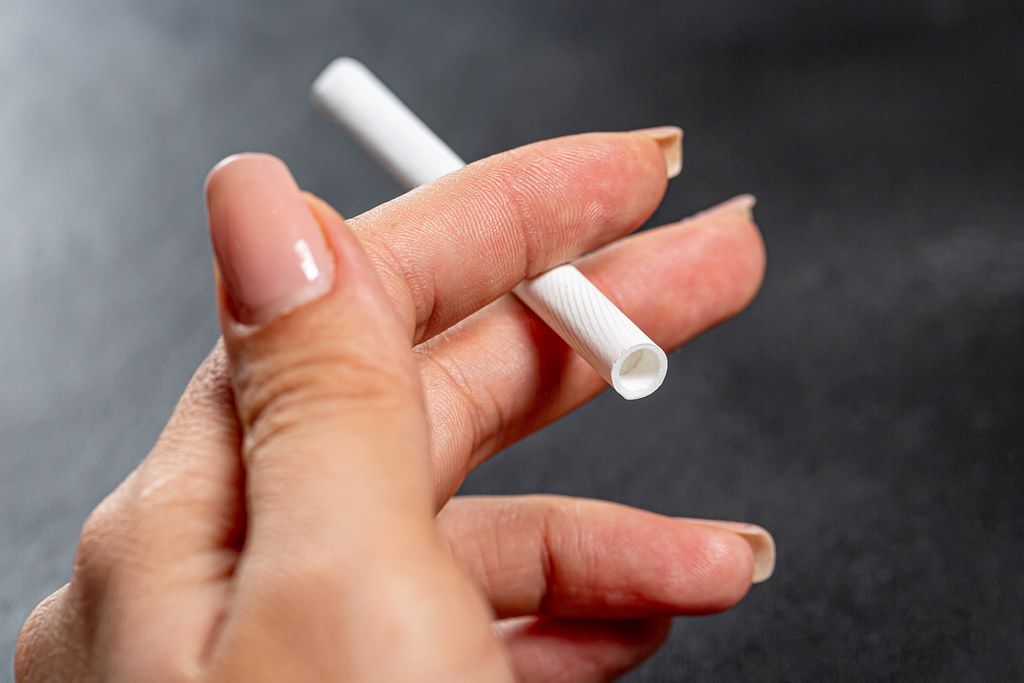 A cigarette in a woman's hand. The concept of addiction and bad habits
