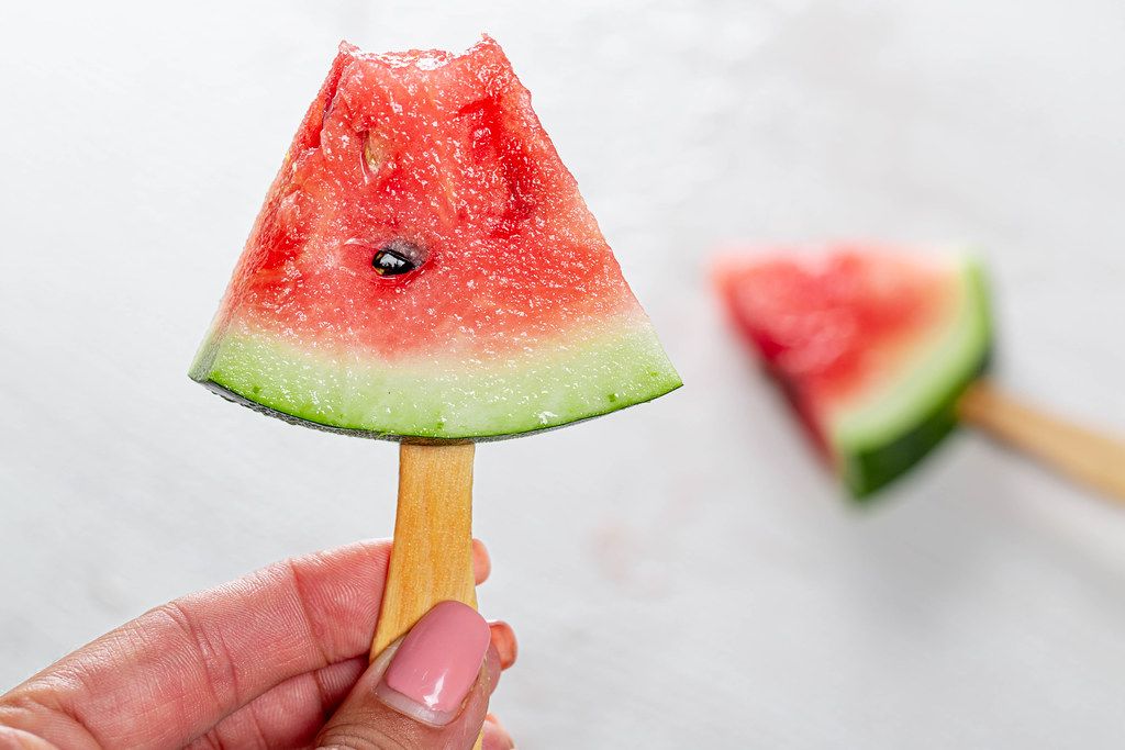 A half-eaten slice of ripe watermelon on a stick