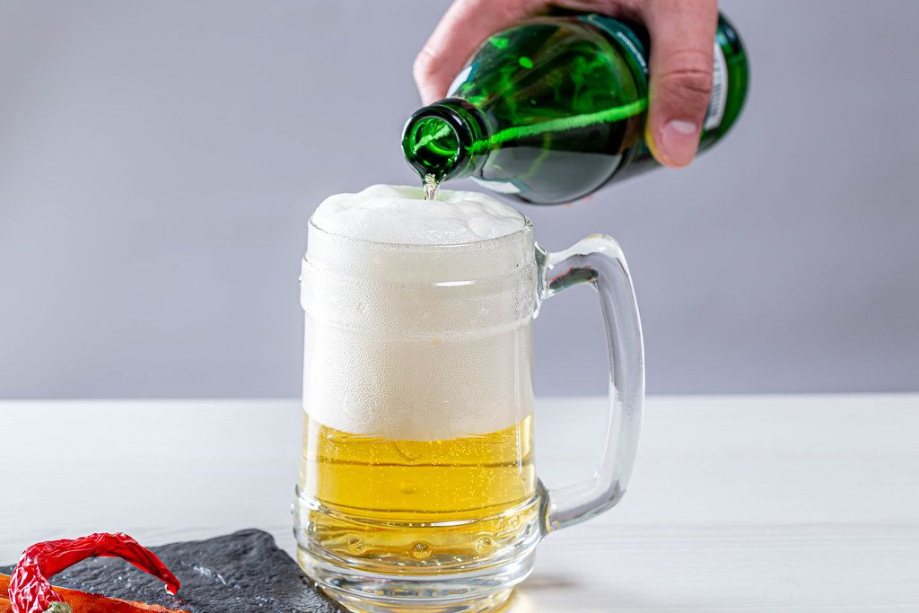 A man pours a bottle of beer in a beer glass