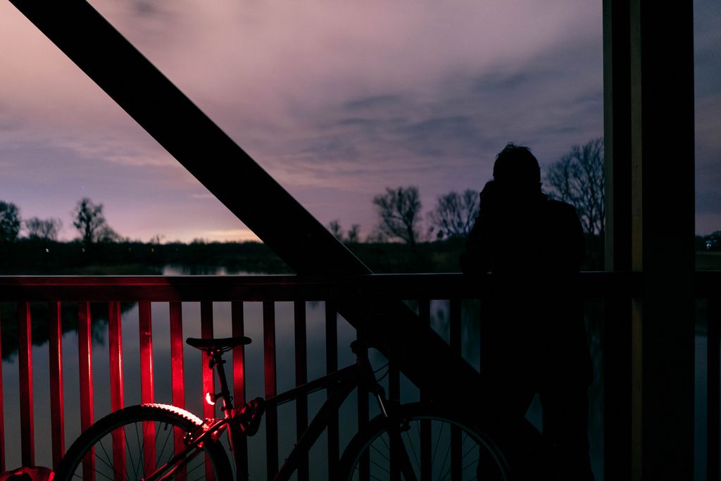 A man taking a picture on the wooden bridge by a bicycle at night (Flip 2019)