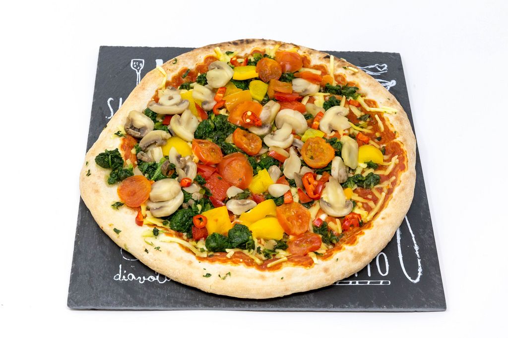 A vegan pizza with mushrooms, peppers, spinach and cherry tomatoes