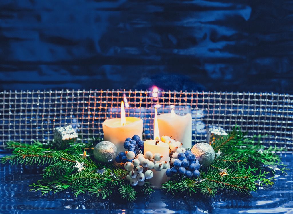 Adventskranz mit weißen Kerzen, silbernen Kugeln und netz auf blauem Hintergrund