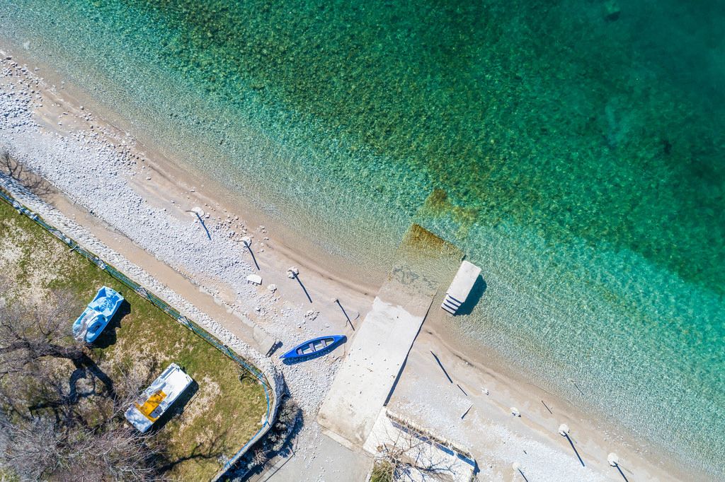 Aerial drone shot of a pebble beach with turquoise water in the winter time