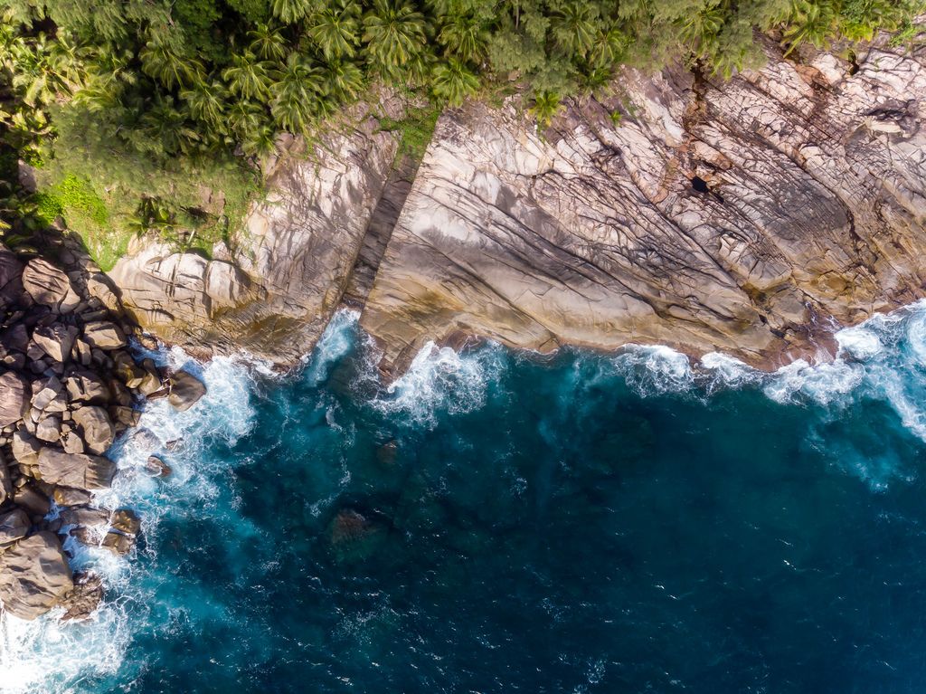 Aerial picture shows waves of the deep blue ocean in front of the cliffs of Ros Lepa in Mahé, Seychelles