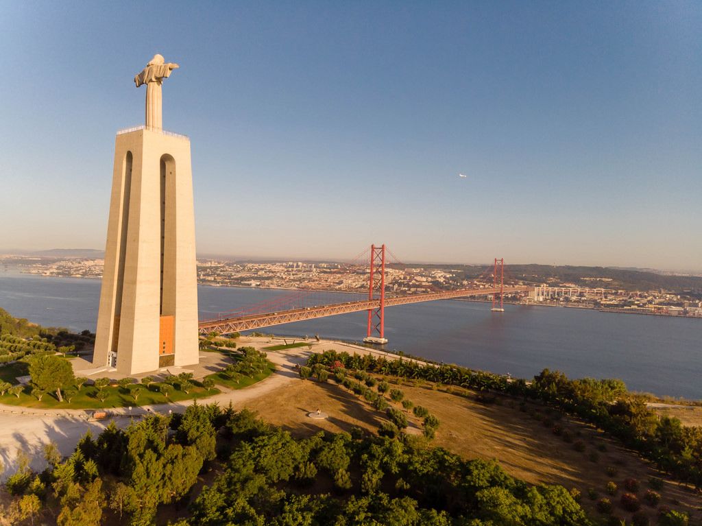 Aerial view drone shot from the side of the Cristo rei monument and the ponte 25 de abril bridge in Almada Lisbon
